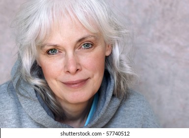 Casual portrait of happy mature woman with natural white hair and minimal makeup.