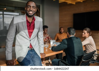 Casual Portrait Of Professional Black African Business Man, Coworkers Hold A Meeting In Background