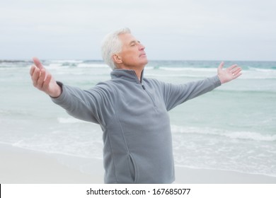 Casual senior man with arms outstretched standing at the beach - Powered by Shutterstock