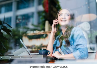 casual smart asian female entrepreneur small business working at coworking space hand using smartphone and tablet business talking consulting shooting through window glasses garden reflecting view - Powered by Shutterstock