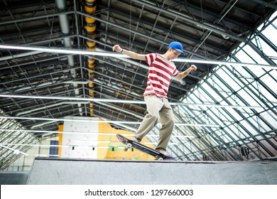 Casual teenage guy standing on skateboard while practicing parkour stunt on special area or stadium - Powered by Shutterstock