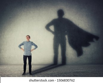 Casual Teenage, Keeps Arms On Hips Smiling Confident, Casting A Superhero With Cape Shadow On The Wall. Student Ambition Success Concept. Leadership Hero Power, Motivation And Inner Strength Symbol.