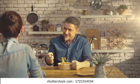 Casual White Couple Eating Take Away Pasta From Food Box At The Table In Kitchen At Home.