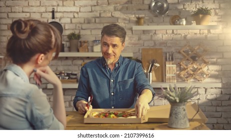 Casual White Couple Eating Take Away Pizza From Food Box At The Table In Kitchen At Home.