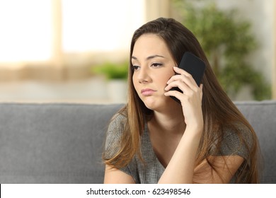 Casual Woman Bored During A Phone Call Sitting On A Couch In The Living Room In A House Interior With A Homey Background