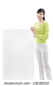 casual woman standing behind a blank board on white background (green concept) - Shutterstock ID 138180332