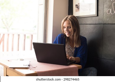 Casual woman using laptop at coffee shop - Powered by Shutterstock