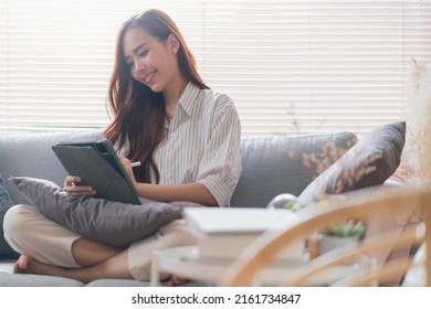 Casual Working At Home Relax Casual Using Tablet Device In Living Room,asian Female Adult Hand Typing Search Or Texting Via Laptop Sofa Working From Home With Happiness Peaceful Smiling Ideas Concept