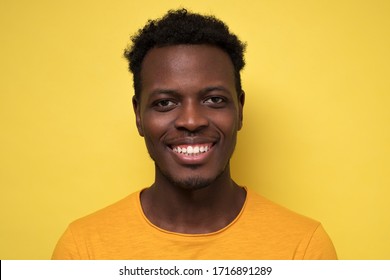 Casual young african man posing in front of camera on yellow background. Close up view.