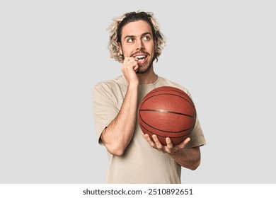 Casual young basketball player in studio relaxed thinking about something looking at a copy space. - Powered by Shutterstock