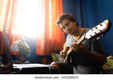 Casual young man with guitar and laptop in bed at home - Powered by Shutterstock