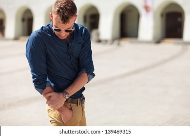 Casual Young Man Reaching Into His Pocket And Looking At It In The City