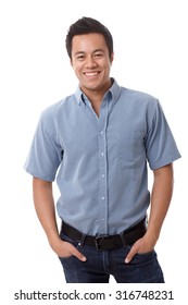 Casual young man in shirt and jeans smiling happy, standing with hands in pockets.