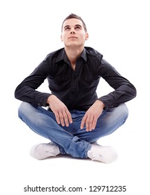 Casual Young Man Sitting Cross Legged On The Floor And Looking Up, Isolated On White Background