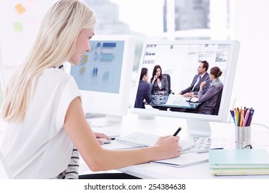 Casual Young Woman Using Computer In Office Against Thoughtful Businesswoman Talking To Her Team During A Meeting