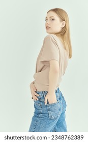Casual youth fashion. A beautiful young blonde girl with a gentle appearance in beige t-shirt and jeans on a white studio background. The concept of people, faces and emotions.