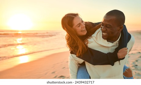 Casually Dressed Loving Couple With Man Giving Woman Piggyback Ride On Beach Shoreline At Sunrise - Powered by Shutterstock