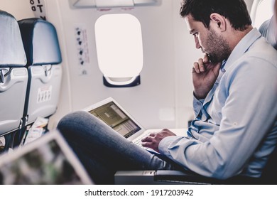 Casually Dressed Middle Aged Man Working On Laptop In Aircraft Cabin During His Business Travel. Shallow Depth Of Field Photo With Focus On Businessman Eye.