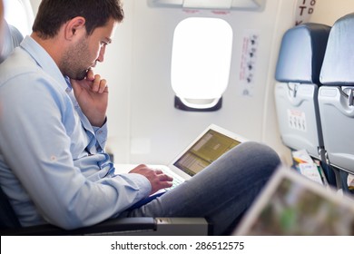 Casually Dressed Middle Aged Man Working On Laptop In Aircraft Cabin During His Business Travel. Shallow Depth Of Field Photo With Focus On Businessman Eye.