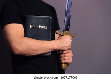 Casually dressed strong young guy standing ready with his Bible and sword