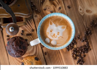 Cat foam face of latte art coffee in cup with scattered coffee beans and biscuits on old wooden table