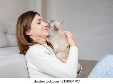  cat licks the nose of a young beautiful woman. Burmese cat licking or kissing woman's nose. Cat and owner together - Shutterstock ID 2138084707