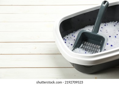 Cat Litter Tray With Filler And Scoop On White Wooden Floor, Closeup. Space For Text