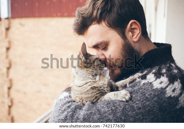 猫と男性 幸せな猫のポートレートと若い男性 子猫と遊ぶ人々 灰色の飼い猫のペットを抱きしめ 抱きしめ 抱きしめる美しい若い動物好きの男性 の写真素材 今すぐ編集