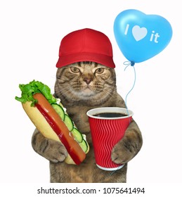 The Cat In A Red Baseball Cap Holds A Cup Of Coffee, A Blue Balloon And A Hot Dog. White Background.