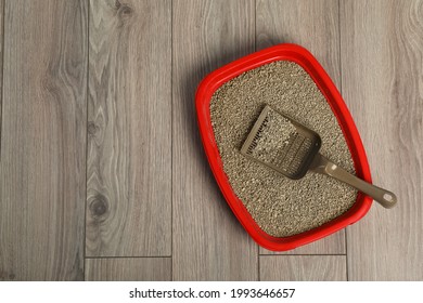 Cat tray with clumping litter and scoop on wooden floor, top view. Space for text - Shutterstock ID 1993646657
