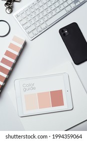Catalog of trendy colors, a keyboard, a mobile phone on a light table. A nude color palette used by a designer to select the right shade. Top view.