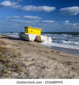 A Catamaran Houseboat Beached On A Florida Beach With Sand Dune In The Foreground And The Horizon In The Background