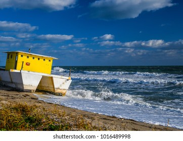 A Catamaran Houseboat Beached On A Florida Beach As Waves Break And Sand Pipers Feed In The Surf