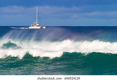 A catamaran off the coast of Kauai with a big wave in the foreground - Powered by Shutterstock