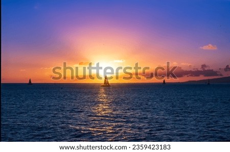Catamaran and sailboats sailing in the ocean against a colorful dramatic horizon at sunset on the ocean in Waikiki Beach Honolulu Hawaii with copy space.