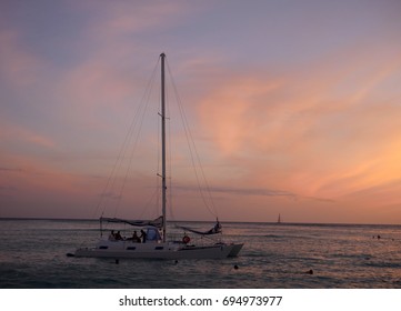 A Catamaran Sailing At Sunset In Waikiki Beach On Oahu, Hawaii. 