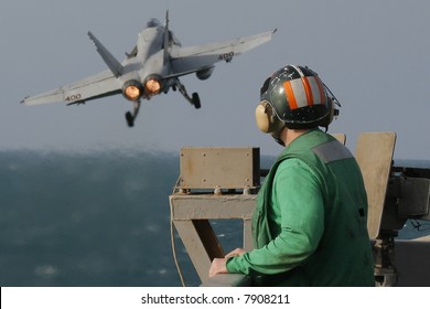 A Catapult Crewman Watches An F/A-18C Hornet Launch From The Nuclear Aircraft Carrier, USS Enterprise