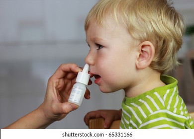 Catarrh - Mother spraying 2 years old baby boy medicine in nose, nose drops, nose spray.