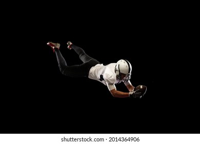 Catch the ball. Portrait young American football player, athlete in black white sports uniform training isolated on dark studio background. Concept of professional sport, championship, competition
