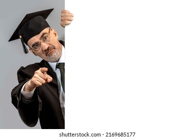 Catch In Plagiarism Concept. Angry Academician, Professor, Prof Is Wearing A Cap With Tassel And Black Gown Pointing Finger At The Camera. Senior Educator Man University Or College. White Copy Space.