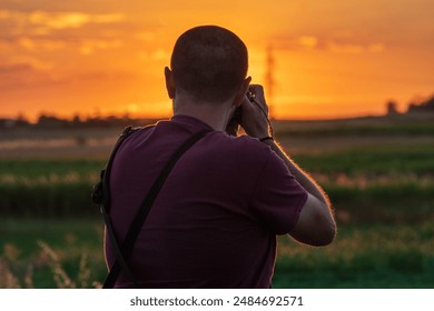 Catcher of the Sun: Photographer Capturing Sunset, Shot from Behind - Powered by Shutterstock
