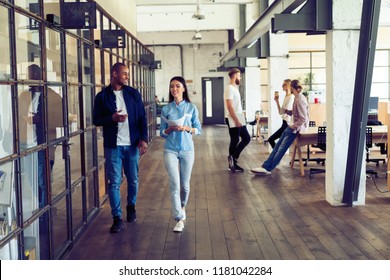 Catching Up Before Meeting. Full Length Of Young Modern People In Smart Casual Wear Discussing Business And Smiling While Walking Through The Office Corridor