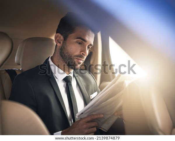 Catching up on the latest news. Cropped shot of a\
handsome young businessman reading the paper while on his morning\
commute to work.