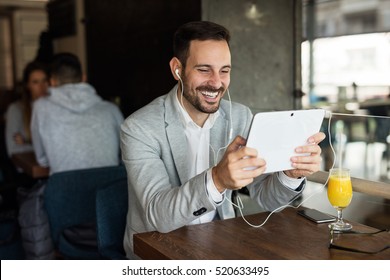 Catching up on some online news before work. Young businessman sitting in city cafe. - Powered by Shutterstock