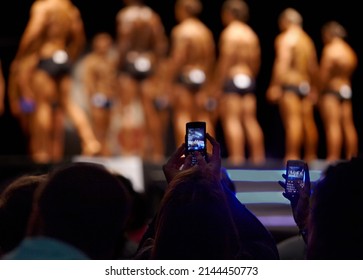 Catching their favourites on camera. The audience of a bodybuilding competition taking photographs of the contestants with their cellphones.