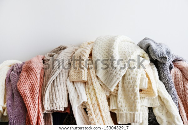 Categorizing winter\
laundry concept. A messy pile of kniwear lying on grey textile\
sofa. Bunch of unfolded sweaters prepeared for sorting. Close up\
copy space,\
background.