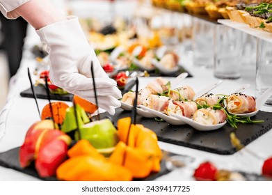 caterer arranges array of appetizers on a serving table, showcasing a variety of fresh and delicious options. scene captures a professional catering event with an emphasis on presentation and variety. - Powered by Shutterstock