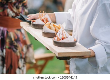 Catering service. Waiter carrying a tray of appetizers. Outdoor party with finger food, mini burgers, sliders.