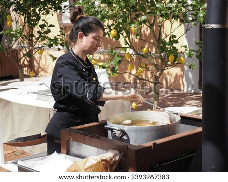 catering staff woman chef cooking and frying at the buffet table of an event