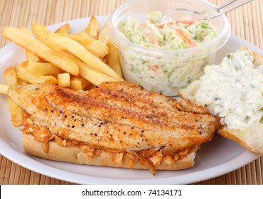 Catfish Fillet Sandwich With French Fries And Coleslaw On A Plate